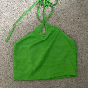 Grön ribbad halterneck linnetopp från Zara - Snygg grön ribbad linnetopp med halterneck och knyt i nacken Zara. Toppen har en liten cut-out framtill och är croppad i modellen. Perfekt för dig som gillar färg och vill sticka ut lite extra.