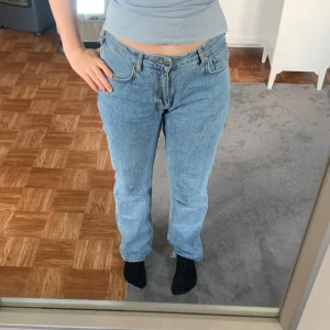 Ljusblå low waist straight jeans - Säljer ett par ljusblå jeans med låg midja och raka ben. Klassisk femficksmodell i denim med dragkedja och knapp framtill. Perfekta för dig som gillar en avslappnad och tidlös look.
