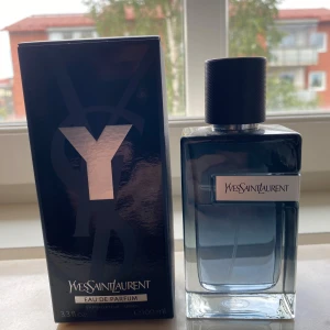Yves Saint Laurent Y Eau de Parfum - Y Eau de Parfum från Yves Saint Laurent i en stilren, rektangulär glasflaska med mörkblå toning och svart texturerad kork. Flaskan rymmer 100 ml och har en metallisk etikett med loggan. Kommer med originalkartong i svart med silverdetaljer. Mängd enligt bild. Kvitto finns, skriv vid minsta lilla fundering.
