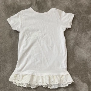 vit volang t-shirt - mycket fin t-shirt med på sydd volang längst ner💓en vanlig basic vit t-shirt från lager 157 i storlek 130, men den är mycket stor i storleken och passar mig som är xxs. volangen är somsagt på sydd men sitter fast väldigt bra 
