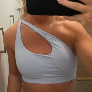 Ljusblå one shoulder sport-bh DFYNE - Säljer en ljusblå sportig topp från DFYNE med unik one shoulder-design och cool cut out-detalj framtill. I modellen impact i färgen ice blue