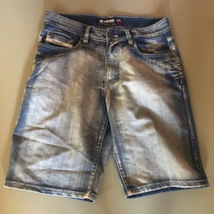 Ecko Unltd Jeansshorts  - Snygga blå jeansshorts från Ecko Unltd med klassisk femficksdesign och slitna detaljer. Shorts i längre modell med normal passform och tydlig tvättad effekt. Perfekta för en chill streetwear-look i sommar!