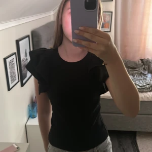 Svart ribbad topp med volangärm Zara - Svart ribbad topp från Zara med  volangärmar. 