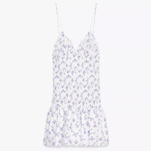 Vit blommig kortklänning med volang - Supersöt nästan slutsåld klänning från Zara med lapp kvar. Klänningen är vit med små blå och lila blommor, smockad midja och volang nertill. Perfekt till sommaren. Klänningen säljs pågrund att den var för kort för mig som är 177 cm🌸