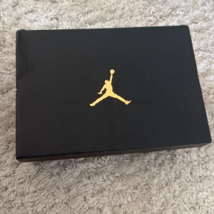 Nike Air Jordan 1 Low svart/rosa - Nike Air Jordan 1 Low sneakers i svart och vitt med rosa swoosh och detaljer. Klassisk siluett med vit tåbox, svarta paneler och vit mellansula. Skorna har snörning och är tillverkade i skinn och syntet. Perfekta för dig som vill ha en clean och stilren look med en touch av färg. Skorna är ej använda.