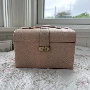 Smyckeskrin - Rosa smyckeskrin med guldiga detaljer💕Den har många olika fack och lådor vilket gör den väldigt praktisk. Bredvid spegeln kan man sätta fast örhängen som extra förvaring. Jag vet tyvärr inte vart det är köpt. Tillhörande hänglås följer med. Utanpå finns några få små fläckar (syns på bilderna). Annars är utsidan i mycket bra skick. Insidan har större tecken på användning då den har några fläckar samt lite smutsig. Alla bruna fläckar är gammalt lim från själva smyckeskrinet☺️