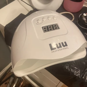 Luunails UV-lampa  - UV-lampa från Luu Professional i vit plast med digital display och timerknappar för 10s, 30s, 60s och 99s. Perfekt för att härda gelnagellack hemma eller i salong. Modern design med öppning framtill för enkel användning. 54 watt