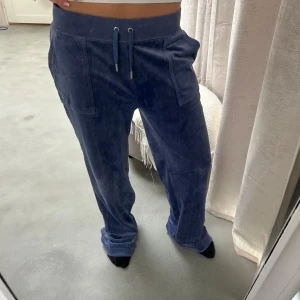 Blå mjukisbyxor med snörning - Mysiga blå mjukisbyxor i velour med bred resår i midjan och snörning framtill. Byxorna har raka ben, stora fickor fram och en bakficka med knapp. Perfekta för chill dagar eller när du vill vara extra bekväm.🥰🥰