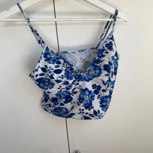 Blommig blå och vit top - Kort blommig top med smala axelband💙 Använd 1 gång. Klippte dock av lappen när den skulle användas så minns inte vart jag köpt den ifrån och storleken står ej, men upplever den som Small. Skrev HM som märke men ej säker vart den är köpt.