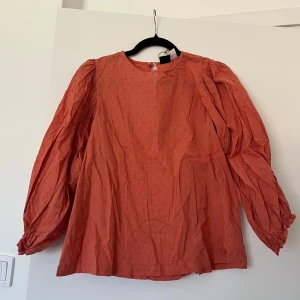 Blus med puffärmar - Säljer en blus med diskret prickigt mönster och voluminösa puffärmar. Blusen har rund halsringning och knäppning bak i nacken. 