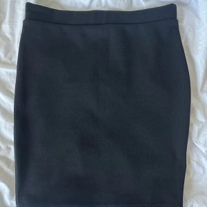 Svart kjol - Enkel och stilren svart tight kjol. Kjolen klassisk rak passform som sitter snyggt på kroppen. Perfekt att matcha med crop tops eller oversized tröjor för en trendig look