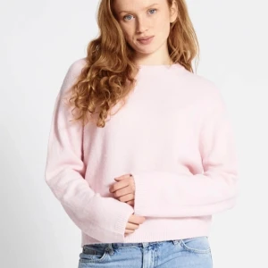 Ljusrosa stickad tröja - Supermjuk ljusrosa stickad tröja med rund hals och långa ärmar. Tröjan har en relaxed passform och ribbade muddar vid ärmslut och nederkant. Perfekt att slänga på sig till jeans.