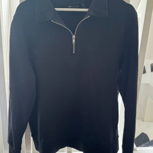 Svart half zip tröja från ASOS Design - Svart långärmad tröja från ASOS Design med krage och snygg half zip-dragkedja framtill. Enkel och stilren modell som passar perfekt till jeans eller mjukisbyxor. Skön bomullskänsla och normal passform.
