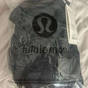 Svart vindjacka från Lululemon - Snygg svart vindjacka från Lululemon med figurnära passform och hel dragkedja framtill. Jackan har höga krage, två fickor med dragkedja och diskret logga på bröstet. Perfekt för dig som gillar sportig och stilren look.