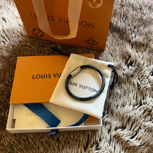 Louis Vuitton armband - Snyggt svart armband från Louis Vuitton i cowhide med silverfärgat magnetlås. Låset har diskret Louis Vuitton-gravering och armbandet skickas med original tillbehören. Perfekt accessoar för att lyfta din outfit säljer den för att den inte kommer till användning, vid frågor eller intresse är det bara att höra av dig 👍
