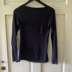 Intimissimi Mörkblå långärmad cashmere tröja - En basic mörkblå långärmad tröja från intimissimi i tunn, lätt och stretchig bomull. Modellen är figurnära med rund halsringning och passar perfekt till lager-på-lager. Enkel och stilren design utan tryck eller detaljer.