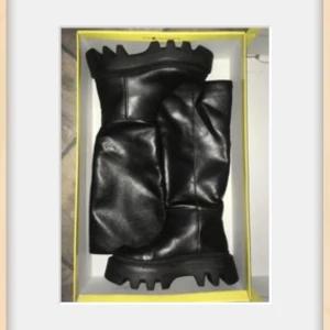 Buffalo svarta vegan boots med platåsula - Buffalo boots i svart veganskt material med chunky platåsula och grovt mönstrad yttersula. Höga skaft och rund tå ger en edgy vibe. Perfekta för dig som vill sticka ut med en cool och modern look. PETA-godkända och helt veganska. Har väck framtill som syns på bild.. Något mer på den ena.. Kartongen lite skadad, kanske Oviktigt men vill nämna.  Säljer då dom inte passar mig.. 