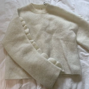 Vit fluffig stickad tröja XS med volang - Jättefin Supermjuk och fluffig vit stickad tröja i storlek XS från arket. Tröjan har långa ärmar och en snygg volangdetalj längs ärmarna som ger en extra touch. Tillverkad i mohair, ull och polyester för en riktigt cozy känsla. Hör av er vid funderingar eller prisförslag❤️❤️
