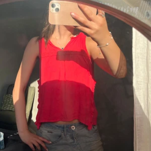 Rödrosa blus med spetsdetaljer!💗 - Superfin luftig blus med broderade spetsdetaljer längs bröstet och volang på sidorna. Färgen är lite mer rosa i verkligheten!🫶🏻 Modellen är ärmlös och har en avslappnad, lite croppad passform. Perfekt för varma dagar och ger en färgklick till din outfit!