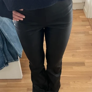 Svarta bootcut byxor i skinnimitation - Snygga svarta byxor i skinnimitation med bootcut-ben och hög midja från Gina tricot i str XS. De har en dragkedja på sidan vilket kan ses på sista bilden och de har vissa ”skrap” märken på slutet av byxan vilket man kan se på bild 3 och 4 men det är inget man ser särskilt mycket när man har de på🤍🤍