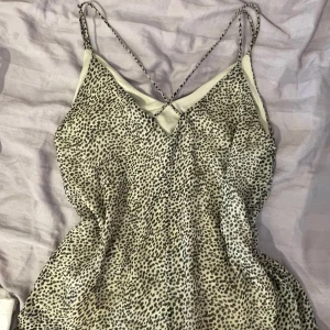 Leopardmönstrad linnetopp med smala band - Säljer en snygg linnetopp med leopardmönster i beige och svart. Toppen har tunna axelband som korsas i ryggen och en lätt v-ringning framtill. Materialet känns svalt och flowy, perfekt för varma dagar eller när du vill sticka ut lite extra.