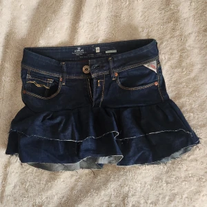 Mörkblå volang jeanskjol Replay - Supersnygg mörkblå jeanskjol från Replay med volangkant och lite fransar. Klassiska fickor fram och bak, coola detaljer. Perfekt för dig som vill ha en edgy och trendig look. Det var jeans från början som jag själv sytt om till en kjol💗Midjemåttet är ca 37, 38cm men stretchiga!