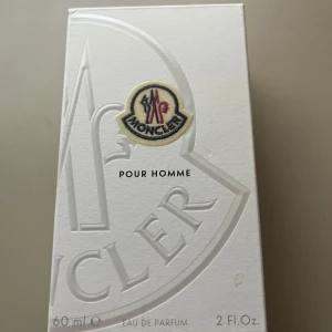 Moncler Pour Homme Eau de Parfum 60ml - Exklusiv herrparfym från Moncler, Pour Homme, 60 ml. Flaskan är i metalliskt silver med räfflad design och Monclers ikoniska logotyp framtill. Kommer i en stilren vit kartong med broderad logga. Perfekt för dig som gillar lyxiga och moderna dofter. (Sprayat ca 3 gånger)