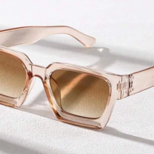 Beige fyrkantiga solglasögon - Snygga solglasögon med transparent beige båge och fyrkantiga linser i en varm brun ton. Ramen är tjock och ger en cool retrovibe, perfekt för dig som vill sticka ut med din stil. Passar till alla tillfällen när solen skiner.