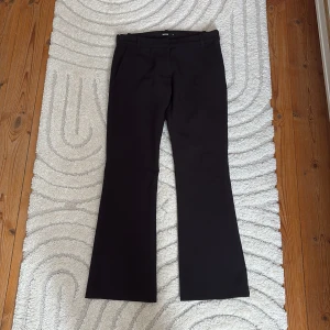 Svarta  kostymbyxor BikBok - Svarta kostymbyxor från BikBok i storlek 34. (Kort längd) passar på längden på mig som är ca 165 cm lång. Byxorna har hällor för bälte och klassiska fickor fram och bak. Snygg passform och stilren look, perfekta till en dressad outfit. På nära håll kan tyget se lite nopprigt ut och har ett litet hål på midjan/höften. Jag kan tänka mig kunna sy igen hålet. Men jag kommer sälja det för billigare pris om jag inte gör det.