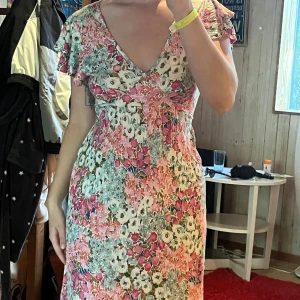 Blommig sommarklänning från Warehouse  - Superfin blommig klänning i rosa, grönt och vitt med v-ringning och volangärmar. Lätt och luftig modell som slutar strax under knäet. Perfekt för varma dagar och har en romantisk vibe med sitt färgglada mönster.