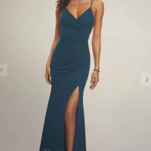 Mörkblå långklänning med slits - Hej! Säljer min Supersnygga mörkblå balklänning från JJ's House med smala axelband, v-ringning och en hög slits framtill. Klänningen har figurnära passform och draperad detalj över bysten. Perfekt för dig som ska på bal eller fest