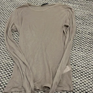 Beige långärmad topp från Zara - Supermjuk och tunn beige långärmad topp från Zara. Modellen är enkel med rund halsringning och smal passform. Perfekt att styla lager på lager eller bära som den är. Materialet är lätt och känns riktigt skönt mot huden.