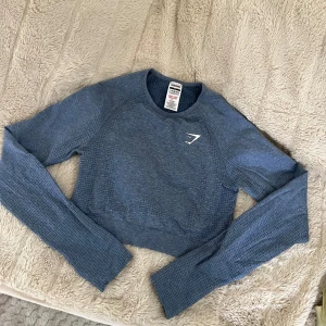 Blå croppad träningströja Gymshark - Säljer en blå croppad långärmad träningströja från Gymshark. Finns även hål för tummarna längst ner vid ärmarna. Mjuk och sitter superskönt. 