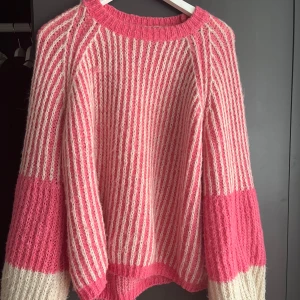 Randig stickad tröja - Superfin stickad tröja med breda ärmar i rosa och beige. Tröjan har ett randigt mönster, rund halsringning och oversized passform.  Storlek S/34, slutsåld! Nelly 