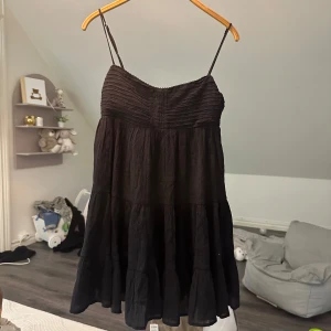 Svart kort klänning från Zara - Supersöt svart klänning från Zara med tunna justerbara axelband och volangig kjol. Överdelen har snygga rynkade detaljer och klänningen är luftig och lätt, perfekt för varma dagar. Enkel att styla med sneakers eller sandaler. Alldrig använd. 