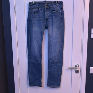 Blå regular fit jeans från Dressmann - Säljer ett par klassiska blå jeans från Dressmann i regular fit. Jeansen har fem fickor, raka ben och snyggt tvättad denim. Perfekta för dig som gillar en tidlös och enkel stil. Storlek 32/34.