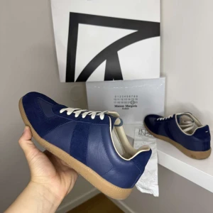 Maison Margiela Gats - Maison Margiela sneakers i mörkblått , kvitto låda och skor får man med vid köp. Skorna är 9/10 sick och är enbart lite smutsiga och repade under sulan vilket är naturligtvis meningen pris går att förhandla och skorna säljs i befintligt sick. Se sista bilden för att se kvittot. Innesulan är bytt från orginal till extra sulorna man får med när man köper dem vilket sänker priset en del! OBS dem är lite mer slitna än vad de var på bilderna men inget farligt