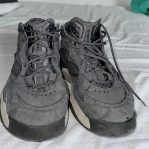 Grå adidas sneakers med snörning - Säljer ett par grå adidas sneakers med coola detaljer och svart-vit sula. Skorna har snörning, rund tå och är tillverkade i en mix av syntet och mocka. Perfekta för dig som gillar streetstyle och vill ha en unik look. De är lite smutsiga men kan tvätta 43 1/3. Lite mjukare vid hälen på vänsterfoten