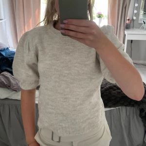 Beige stickad tröja från Gina tricot  - Superfin beige stickad tröja med korta puffärmar och rund hals. Tröjan har en lite croppad passform och ribbade muddar vid ärmslut och nederkant. Perfekt att styla med både jeans och kjol för en trendig look, den är aldrig använd och är i helt nyskick! 🥰 storlek 158/164, passar bra till mig som är 160 men passar även mindre och upp till 170!