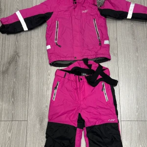 Rosa vinterjacka från North Bend för barn  - Snygg rosa vinterjacka från North Bend med svarta detaljer och reflexband på ärmarna. Jackan har dragkedjor framtill och praktiska fickor. Perfekt för kalla dagar och passar dig som gillar färg och funktion. Materialet är tåligt och håller värmen bra och det förekommer även päls för huvan. (Det går även att köpa enskild) 