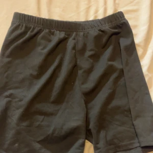 Svarta shorts i polyester med resår - Svarta shorts med elastisk midja, tillverkade i mjuk och stretchig polyesterblandning med 8% spandex. Perfekta för chill dagar eller träning, med enkel och clean design utan mönster eller detaljer.