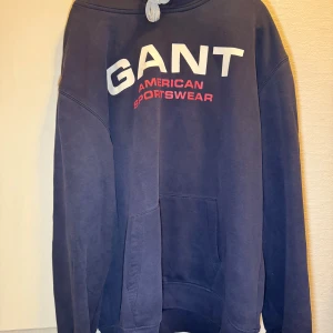 GANT hoodie – stl XXXL - Mörkblå hoodie från GANT med tryck “American Sportswear” på bröstet och broderad logga på ärmen. Skön och rymlig modell. Använd men i gott skick, lite slitage på snörena men inget som stör funktionen.