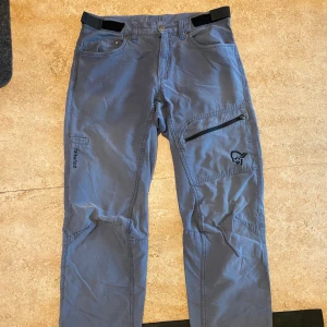 Norrøna grå Falketind byxor S - Säljer ett par blå Norrøna Falketind cotton pants med justerbar midja och dragkedjeficka på benet. Byxorna har raka ben, flera fickor och är tillverkade i en bomulls- och polyamidmix. Perfekta för dig som gillar outdoor och snygg funktion. NYPRIS: 1700kr