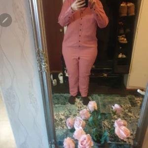 Rosa kostym i linne och bomull - Säljer en snygg rosa kostym med kavaj och matchande byxor. Kostymen har knappar framtill och är tillverkad i en skön mix av linne och bomull, vilket gör den både luftig och bekväm. Perfekt för dig som vill sticka ut med färg och stil.