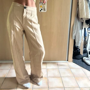 Beiga kostymbyxor från Bershka - Snygga beiga kostymbyxor från Bershka med hög midja och raka ben. 