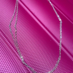 By prisförslag- Dubbel silverfärgat kedjehalsband - Stilrent halsband med dubbla tunna kedjor i silverfärg. Kedjorna har små, runda länkar som ger en klassisk och clean look. Perfekt för att layera med andra smycken eller bära som det är för en minimalistisk vibe.
