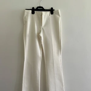 Vita kostymbyxor med bootcut - Snygga vita kostymbyxor från Neo Noir med bootcut-silhuett och pressveck. Byxorna har klassisk midja och raka ben med lätt utsvängning. Perfekta för en clean och stilren look. Materialet känns mjukt och har en lätt stretch. Finns några smutsfläckar - syns inte så värst mycket enligt mig (se bild). 