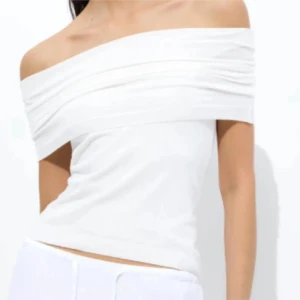 Vit offshoulder topp - Snygg vit offshoulder topp med breda omlottlagda partier över axlarna. Toppens passform är tight och den är croppad, perfekt för en fräsch och stilren look. Enkel att matcha med både jeans och kjol.