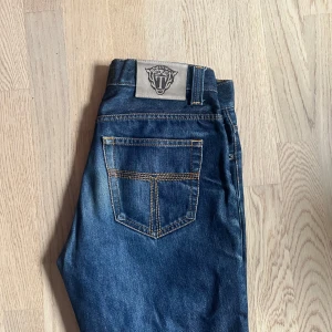 Tiger of sweden blå jeans 29/34 - Snygga blå jeans från tiger of sweden med klassisk femficksdesign och coolt läderpatch med logga bak. Jeansen har raka ben och kontrastsömmar. Storlek 29/34, Säljs för de ej passar mig. Små defekter finns på sista bilden men annars bra skick! Priset ej hugget i sten och kan prutas vid snabb affär!!
