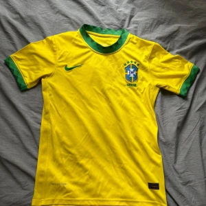 Brasilien Nike fotbollströja gul/grön - Säljer en fotbollströja ”Brasilien” hemmakit från Nike i gult med gröna detaljer. Tillverkad i lätt och ventilerande Dri-FIT-material. Landslagströjan passar både S/M